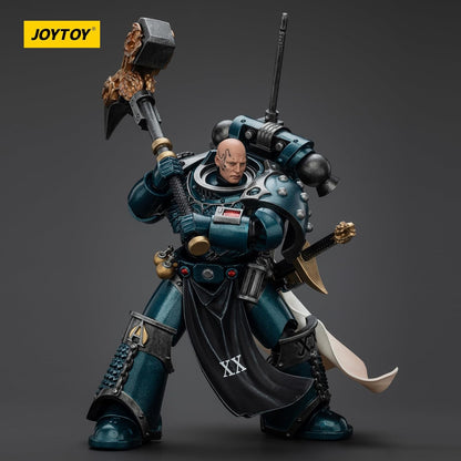 Teal armored Space Marine figure holds an ornate warhammer. He has a bald head and a black loincloth with "XX"