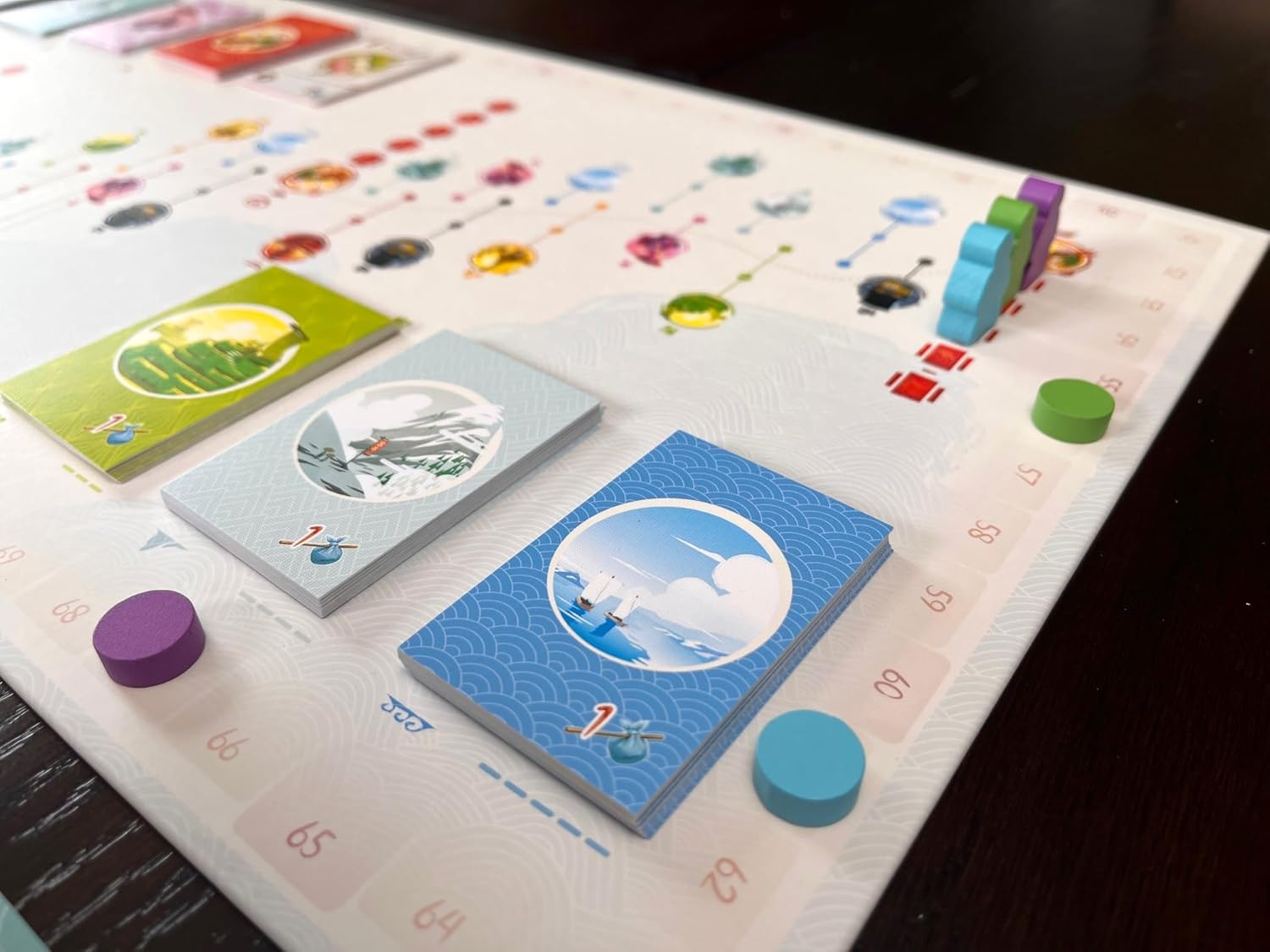 Stacks of scenic cards and wooden player pieces on a board game featuring a score track