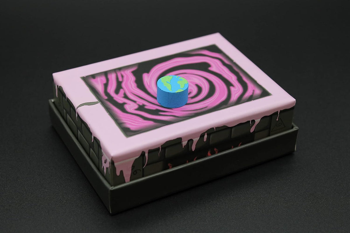 A rectangular box with a pink swirling vortex on its lid, topped by a miniature Earth, pink liquid drips down its dark brick sides