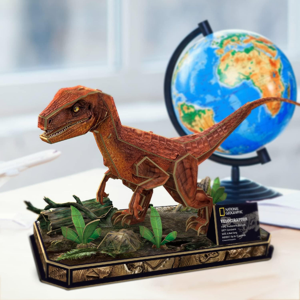 A rust-coloured, segmented Velociraptor model appears to stride on a display base, with a globe behind it