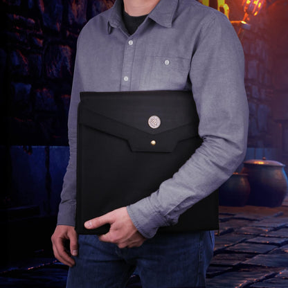 A person holds a black folio with a circular emblem and brass button on a dark, cobblestone path