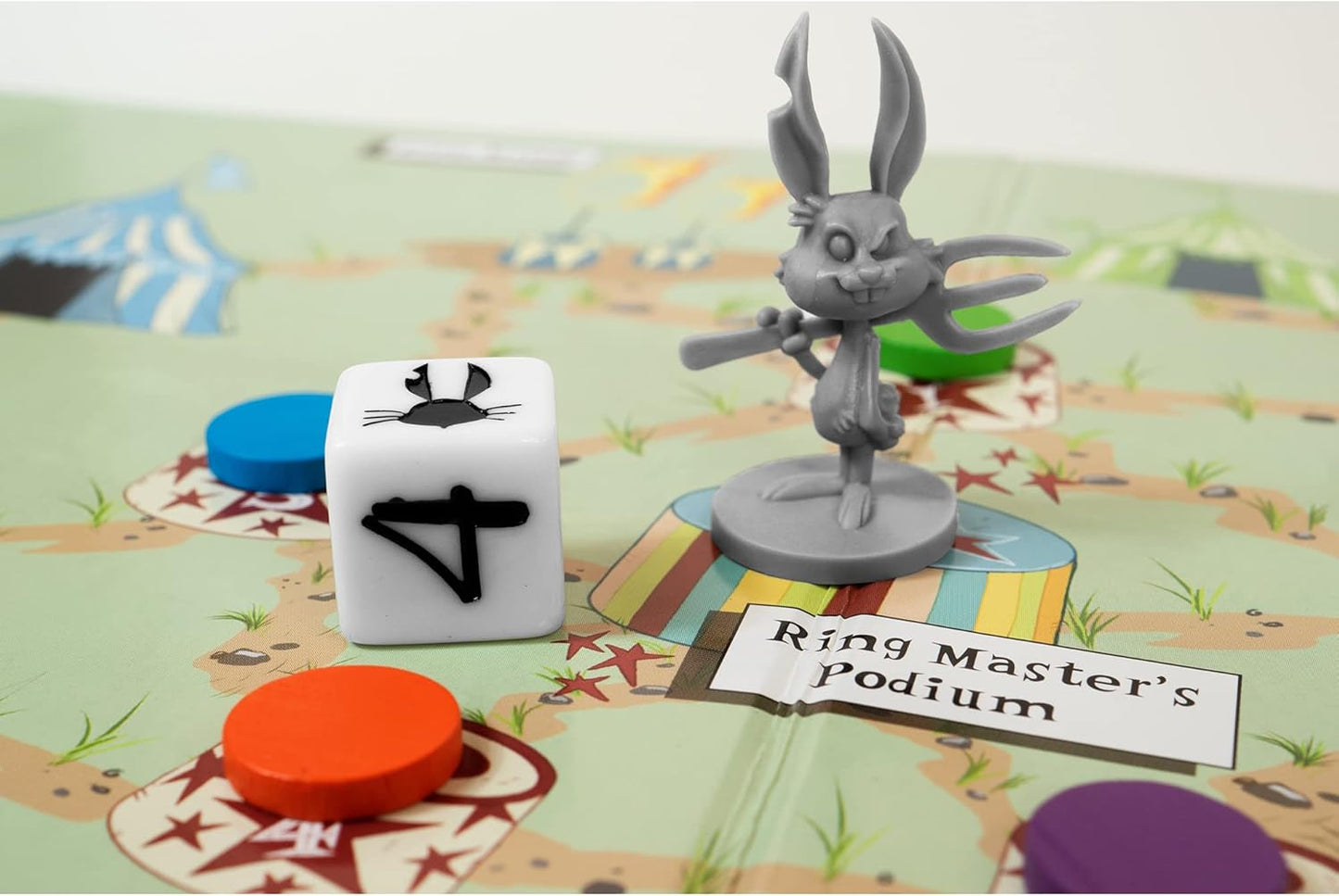 A winking grey rabbit game piece with a pitchfork stands on a "Ring Master's Podium" next to a die on a circus board