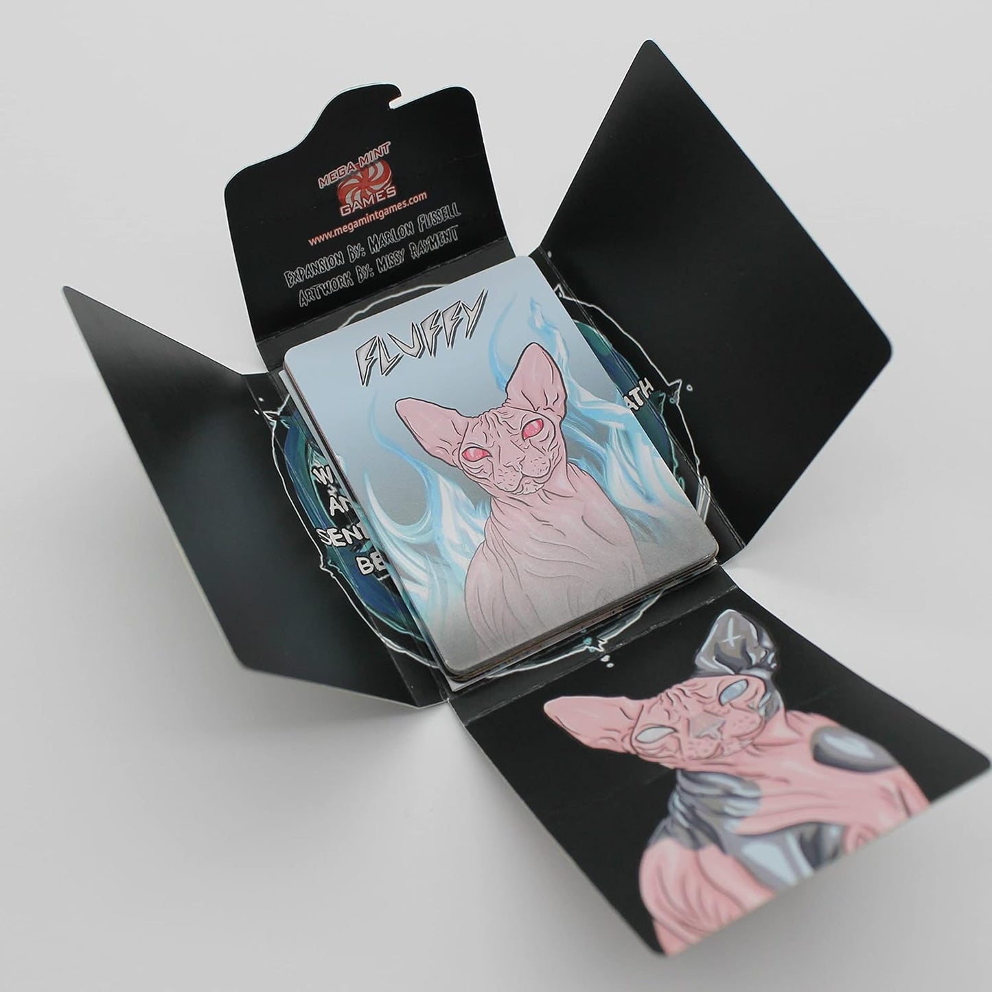Open black game box from Mega-Mint Games, revealing cards with a glowing-eyed Sphinx cat named "Fluffy"