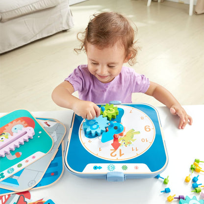 Toddler smiling while actively playing with a blue learning clock and colorful interlocking gears