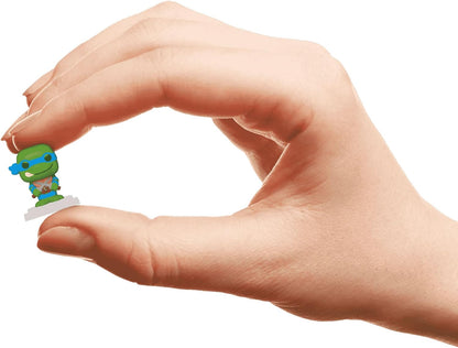 Miniature green Ninja Turtle (Leonardo) figure held between a person's index finger and thumb