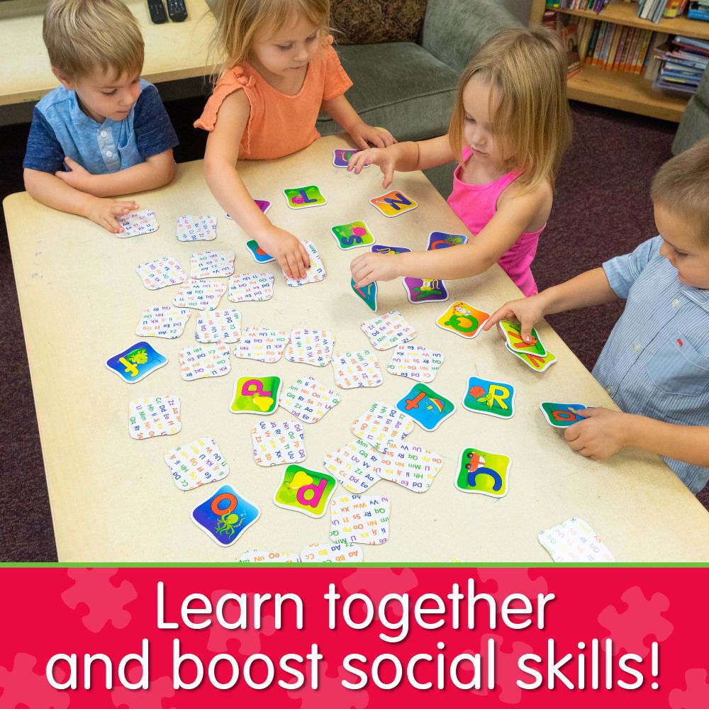 Four young kids playing an alphabet matching game with letter flashcards on a table