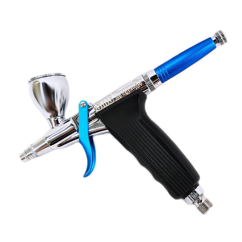 A silver and black trigger-style airbrush with a blue handle top and trigger, and a small cup on top, on a white background