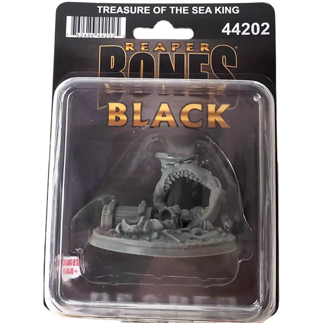 A grey unpainted Reaper Bones Black Treasure Of The Sea King miniature in a clear plastic blister pack with black backing, showing a monster&#39;s open mouth over bones and a chest