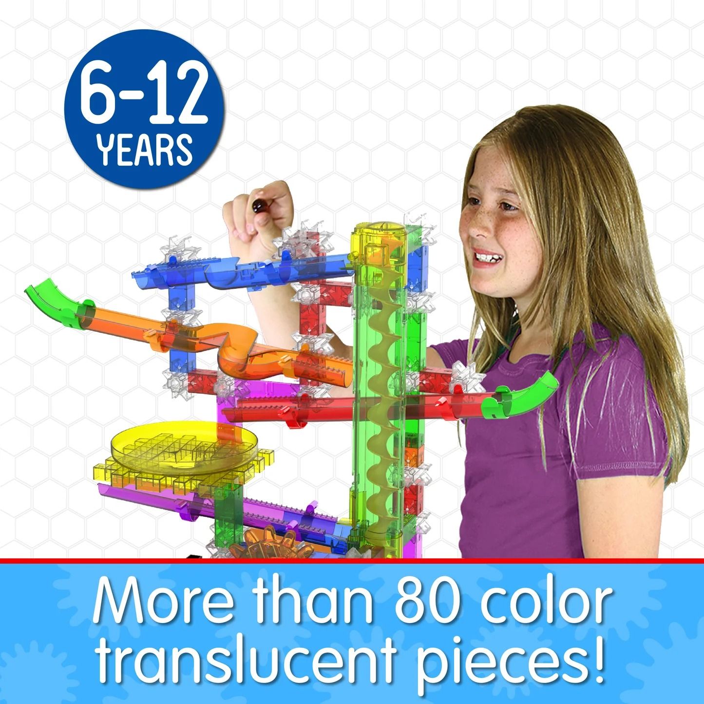 Smiling girl building a colourful, translucent plastic marble run structure