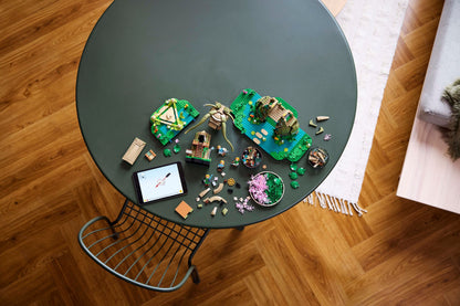 LEGO fantasy models, loose bricks, and minifigures on a green table next to a tablet showing building steps