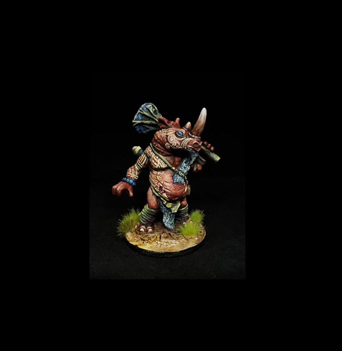 Painted miniature of a tribal rhino warrior holding a staff over its shoulder
