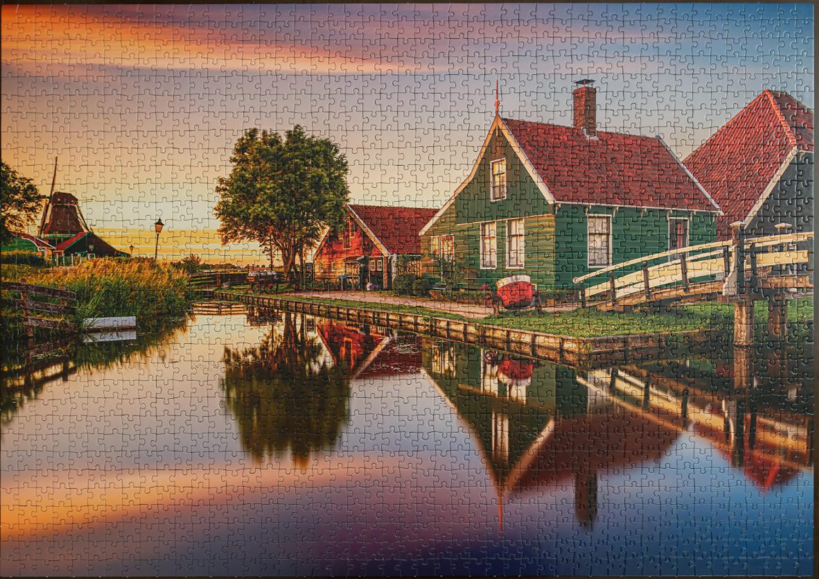 A completed Clementoni Zaanse Schans 1500 Piece Puzzle showing a scenic Dutch village with canals, houses, a bridge, and a windmill at sunset
