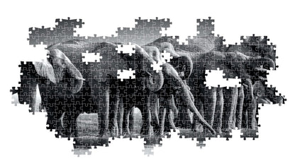 The partially constructed black and white jigsaw puzzle displays a dense grouping of elephants with trunks lowered against a plain white backdrop