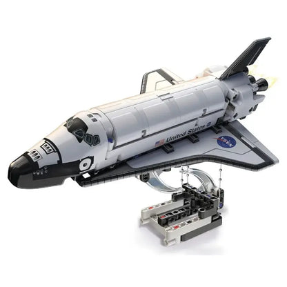 White plastic toy model of a space shuttle on a clear and gray stand with detailed engines and small american flag