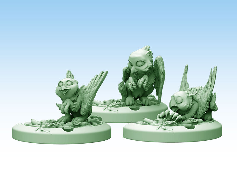 Three unpainted green baby griffin miniatures: one sits, one crouches, one lies, on bases with tiny roses