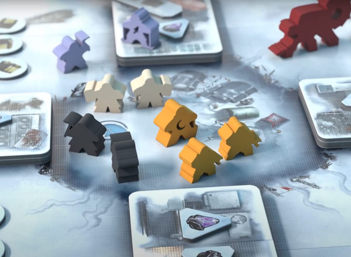 Purple, beige, black, and orange meeples stand on a snowy board game map with cards