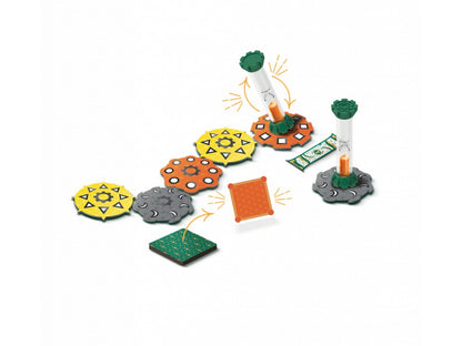 Quicksand game components include colourful patterned tiles, two green hourglass timers with orange sand, an orange card, a green square tile, and a patterned green mat