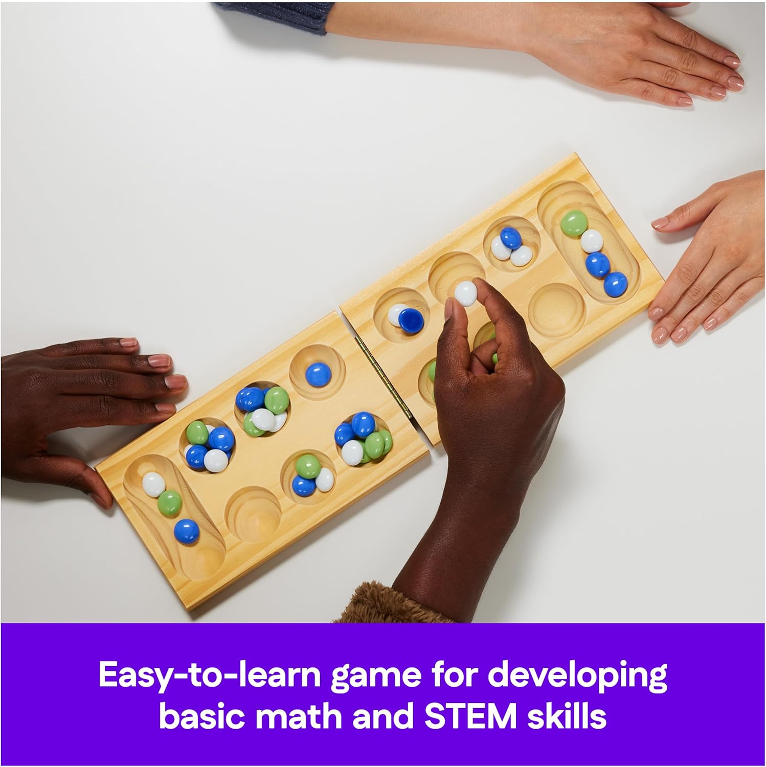 Hands moving a white marble on a wooden Mancala board filled with blue, green, and white playing pieces
