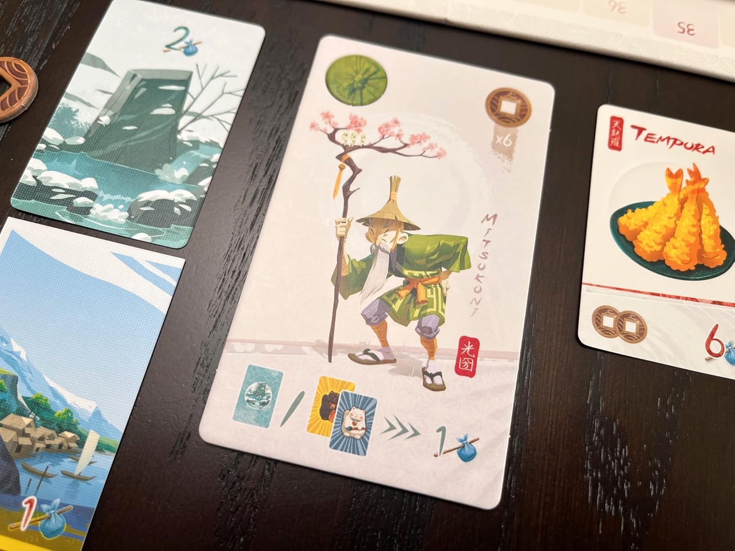 Japanese-themed board game cards, centered on the Mitsukuni traveler character card and a Tempura food card