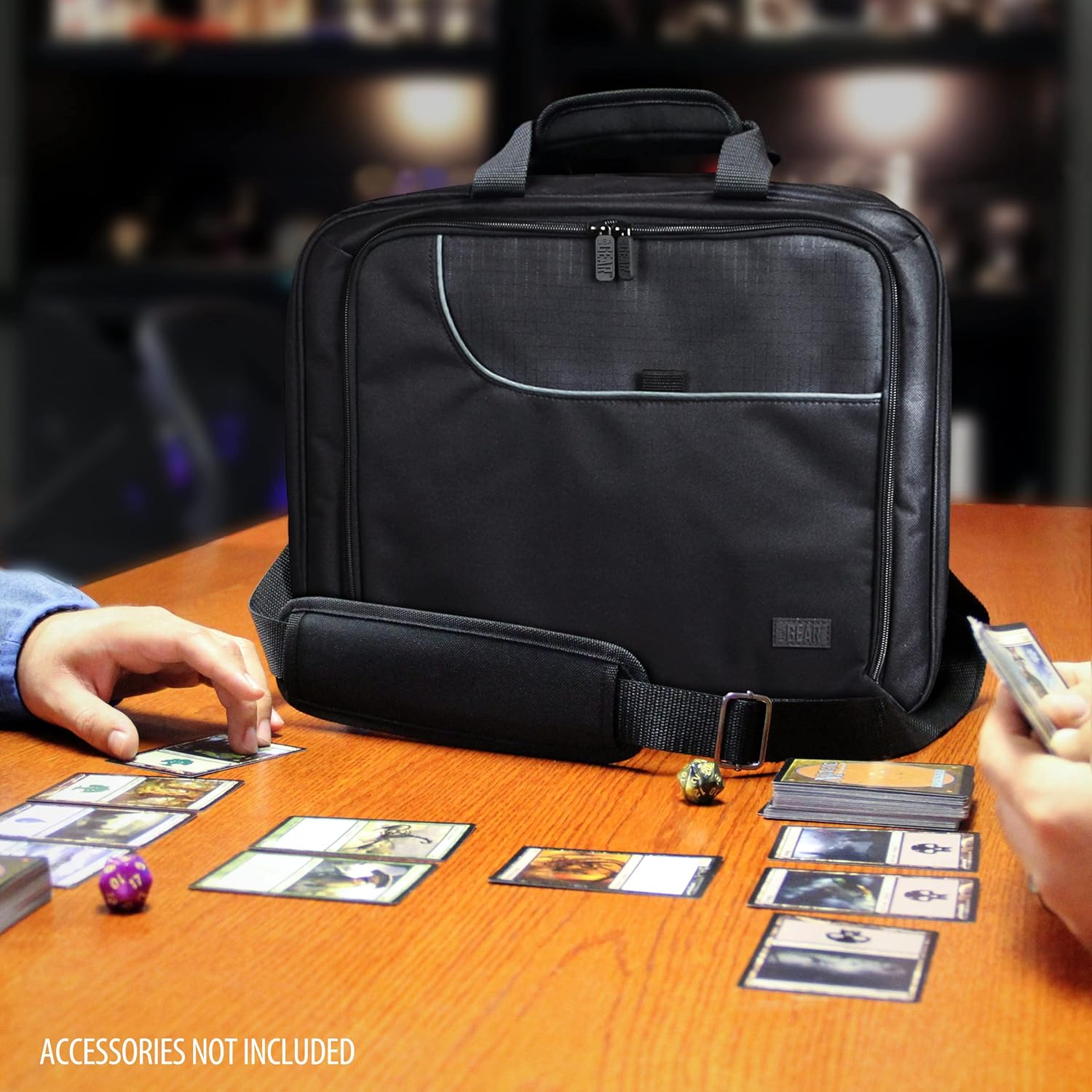 Black game carrying bag on a table with hands playing a card game, featuring cards and dice.