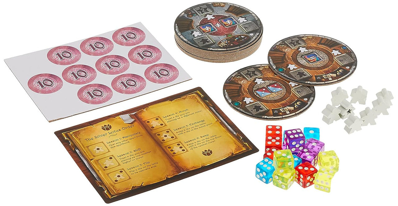 Board game components including a stack of circular player boards a sheet of circular tokens with the number 10 a rulebook open to a page titled The Silver Lotus Order clear multi-colored dice and several white wooden meeples