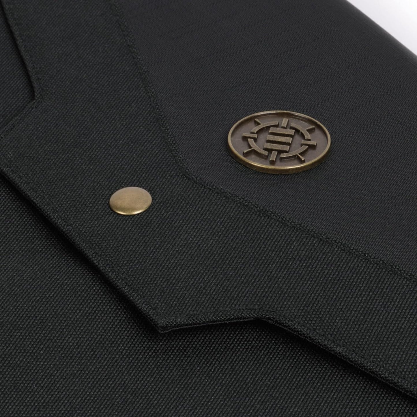 Black textured fabric with a bronze snap and an oval bronze pin etched with an intricate symbol
