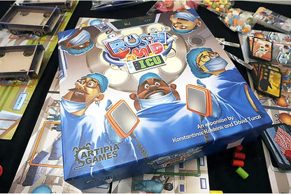 Rush M.D.: ICU Expansion board game box, featuring cartoon doctors with defibrillators, on a table with game components