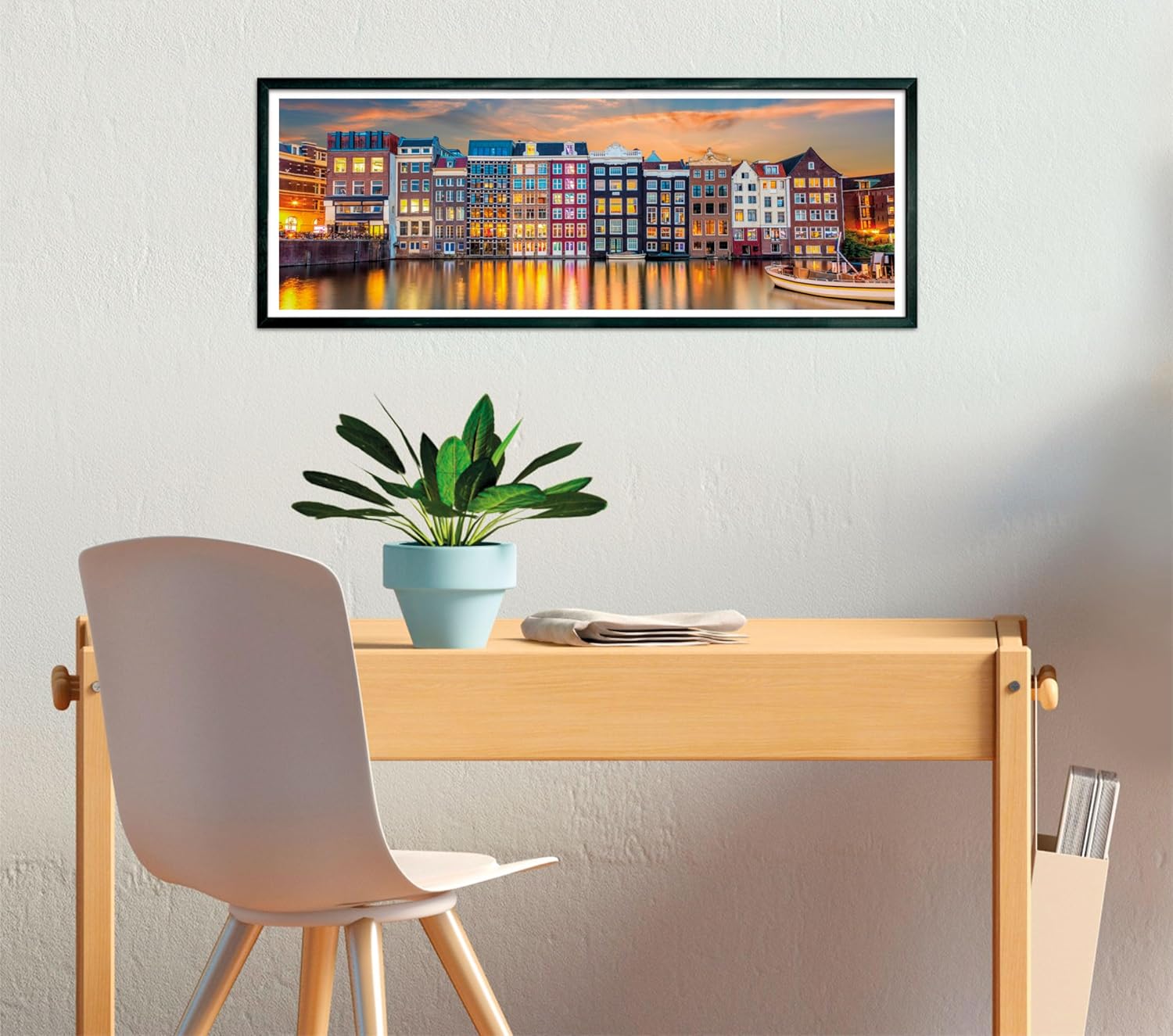 Framed photo of colorful canal houses reflecting on water at twilight, displayed above a minimalist desk setup