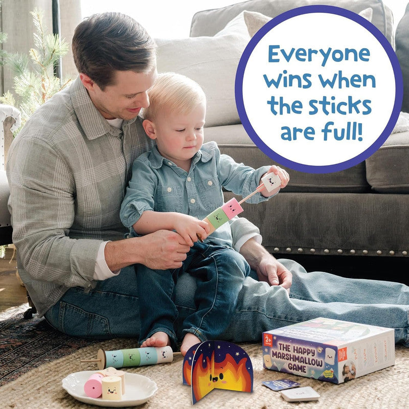 Peaceable Kingdom The Happy Marshmallow Game shows a dad and son playing on the floor with game pieces including a pretend campfire