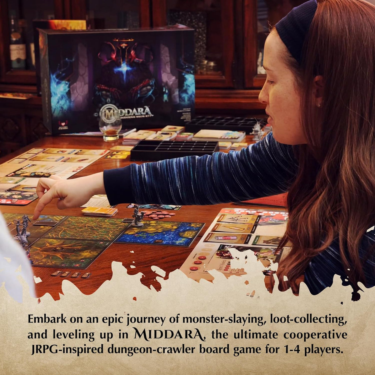 A woman points at a Middara board game setup with miniatures and cards on a wooden table.