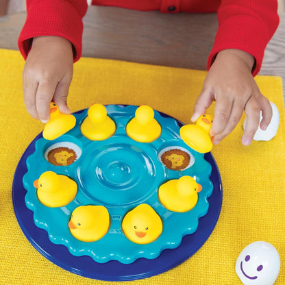 Child plays a matching game, placing yellow rubber ducks on a blue circular toy