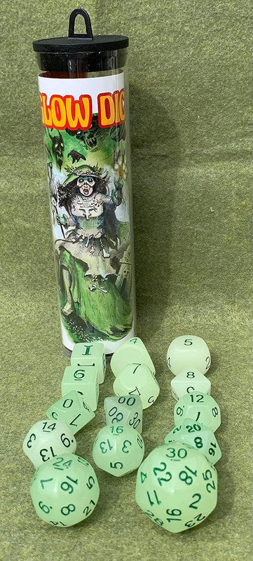 Clear tube with a witch illustration, beside glowing green polyhedral dice on green felt