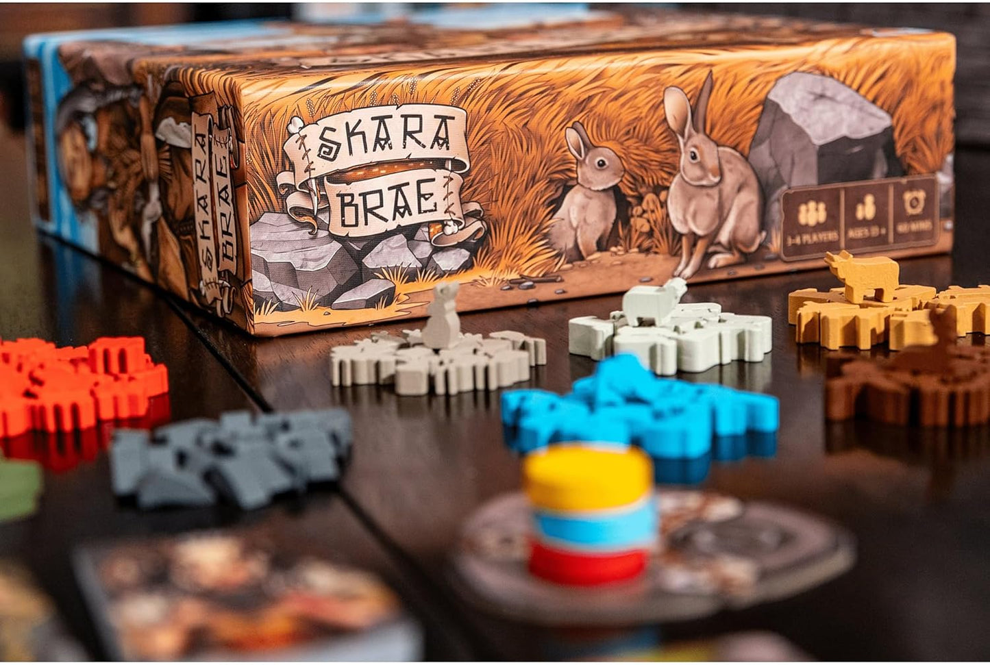 Skara Brae board game box and colorful wooden tokens, including sheep and landscape shapes, on a dark table