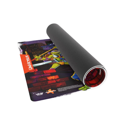 The Teenage Mutant Ninja Turtles Universus playmat featuring vibrant Donatello artwork on a dark city rooftop is shown partially rolled exposing its non-slip rubber backing