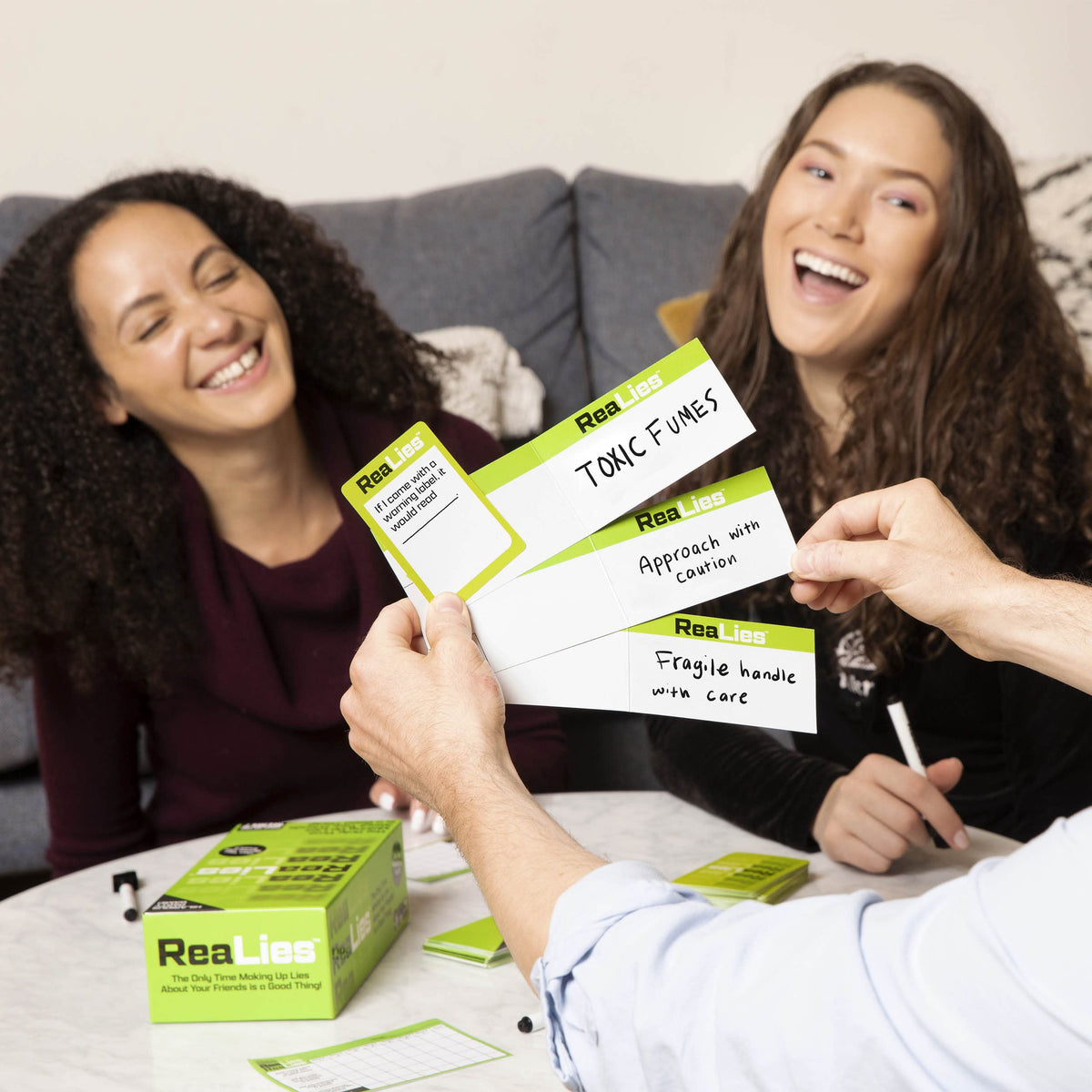 Group of players laughing and interacting with What Do You Meme: ReaLies cards