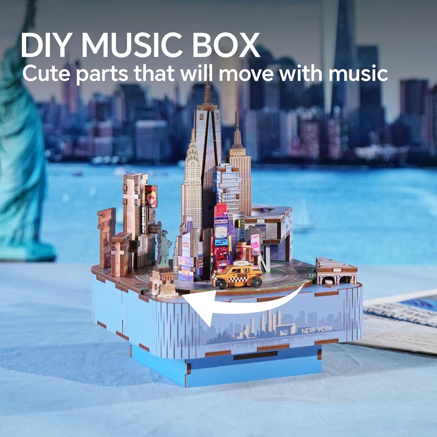 Wooden DIY New York City music box with detailed skyline models and a moving yellow taxi
