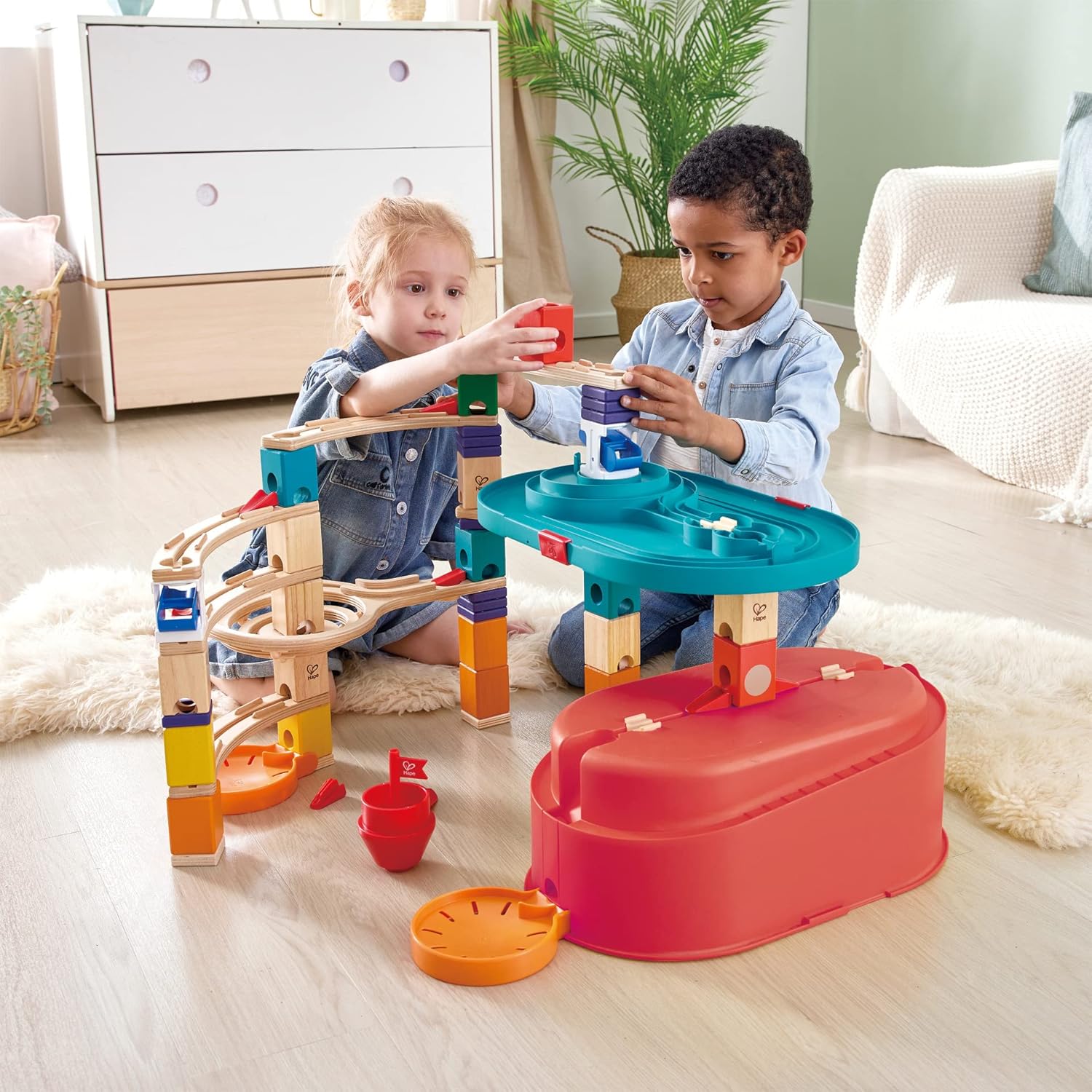 Two children building a colorful wooden block and track marble run toy on the floor