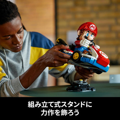 Person carefully positions a built LEGO Mario Kart model over a display stand
