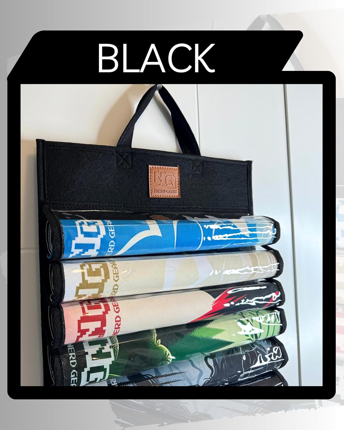 Black felt hanging organizer holding five colorful rolled-up gaming mats in clear pockets