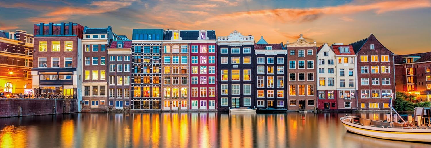 Colorful row of gabled houses reflecting glowing lights onto a dark canal at sunset
