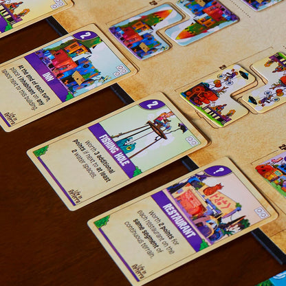 A close-up of three colorful game cards: Inn, Fishing Hole, and Restaurant, from a board game