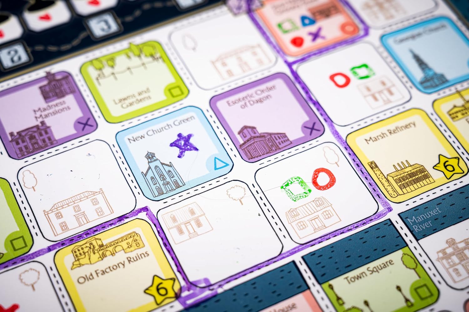Colorful board game map showing labeled location tiles, hand-drawn buildings, and placement symbols