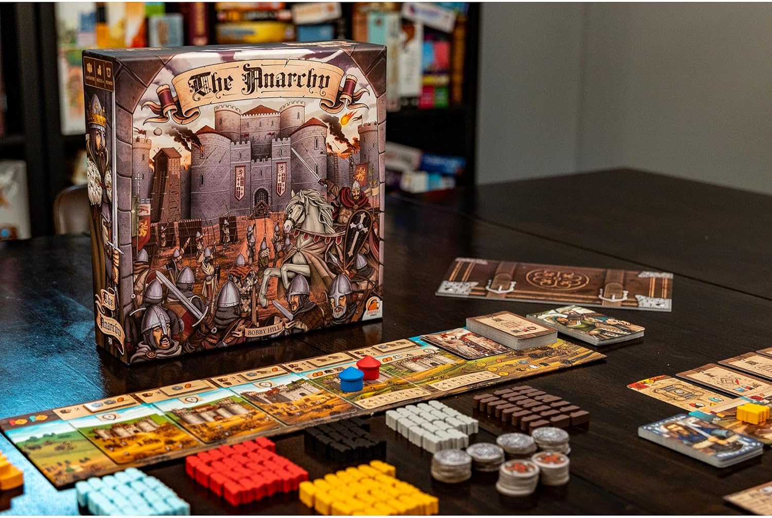 Board game "The Anarchy" set up, showing the box art, game board track, and multicolored wooden tokens