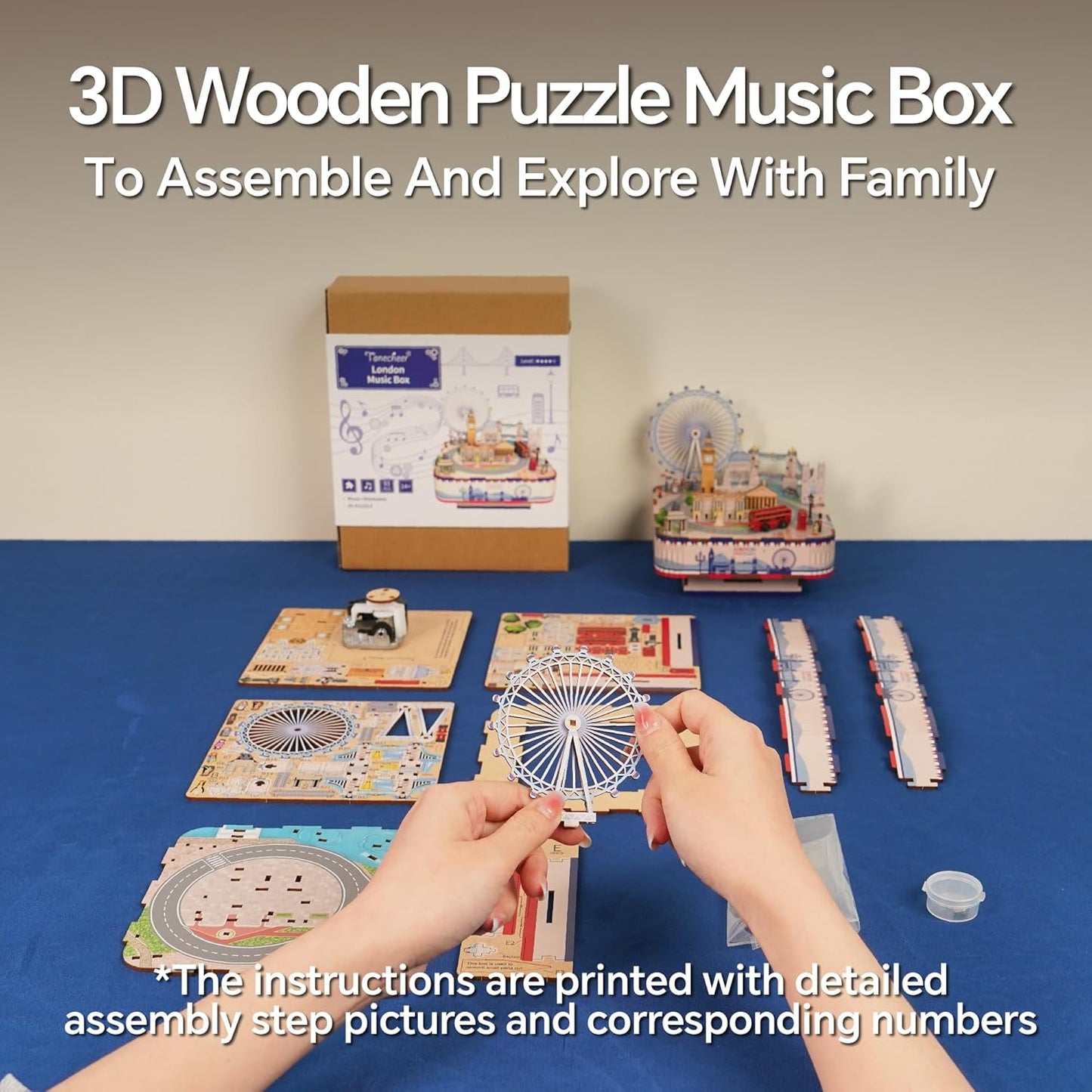 Hand assembling a 3D wooden puzzle music box with London landmarks on a blue table