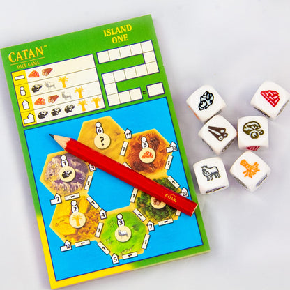 A Catan Dice Game sheet with a red pencil and seven white resource dice showing symbols like sheep, wood, brick, ore, and a brain