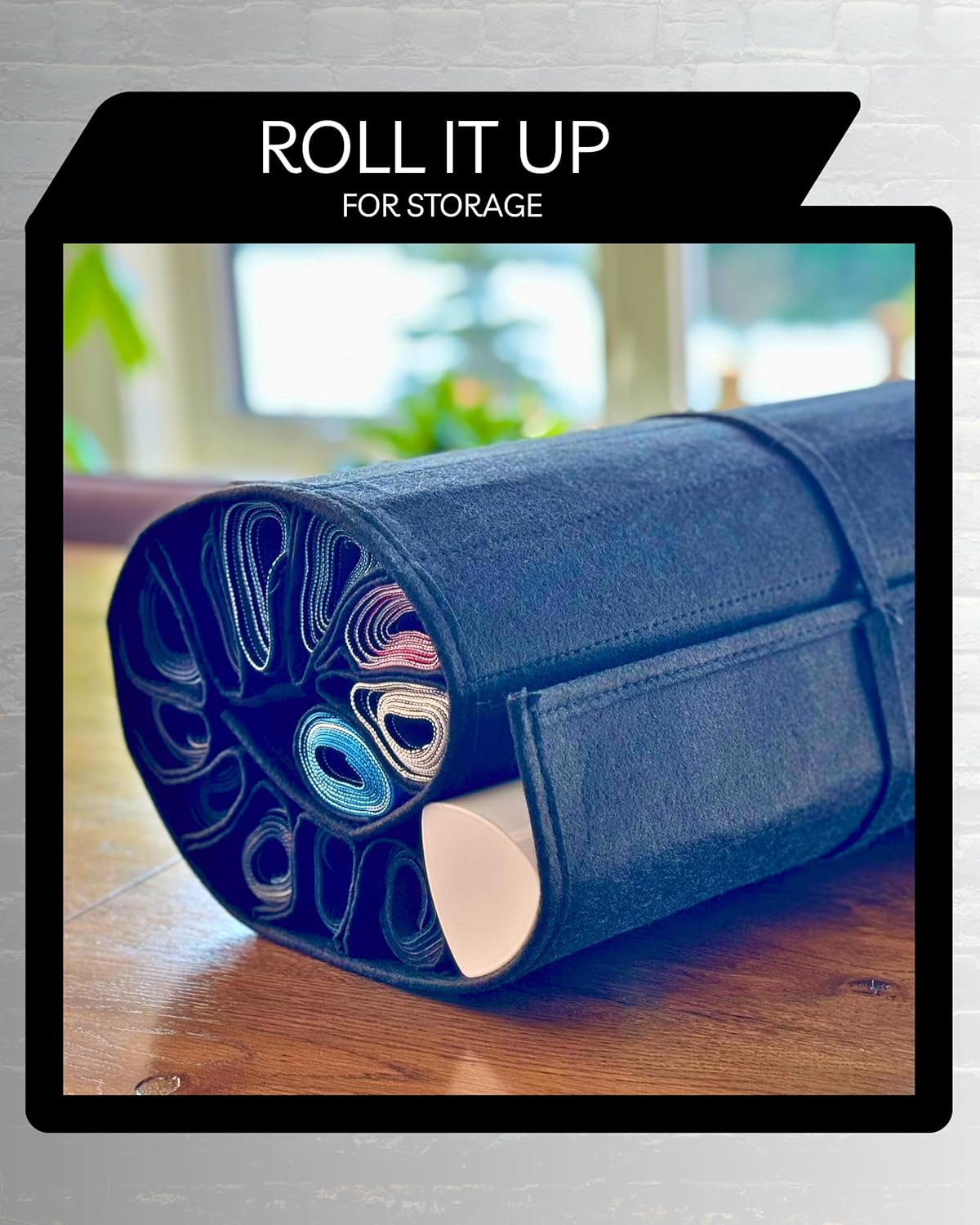 Black felt roll-up storage case holding various small, rolled craft materials on a wooden surface