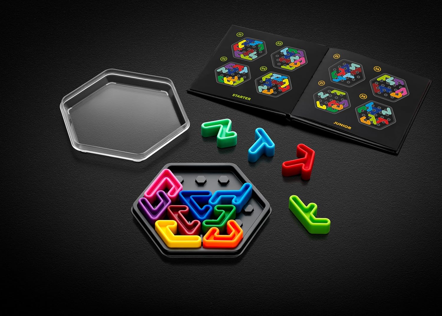 Brightly colored IQ Deluxe Hexagon puzzle pieces, some in a hexagonal tray, next to a challenge booklet