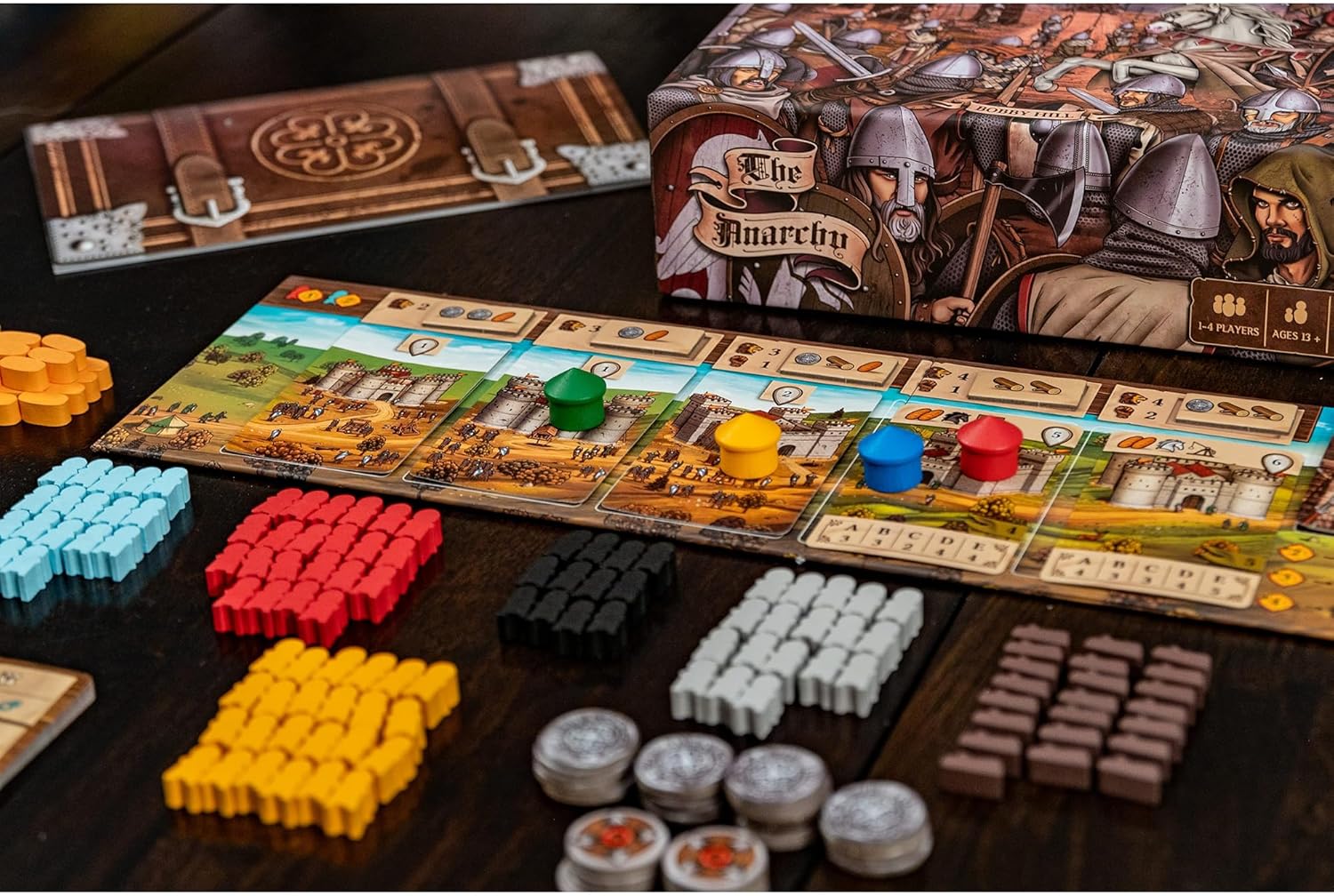 The Anarchy board game setup, showing the modular board, large stacks of colorful wooden meeples, and the box