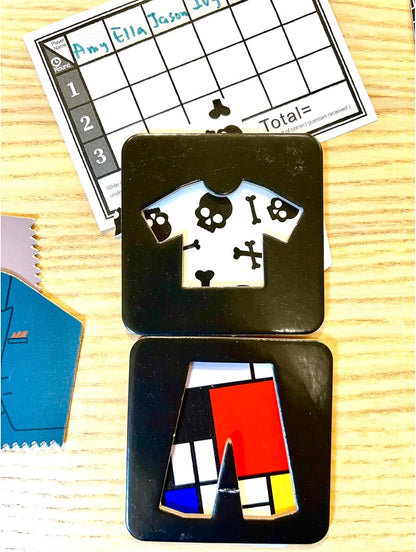 Black game pieces: a shirt with white skulls and crossbones, and pants with Mondrian-style red, blue, yellow blocks. Game score sheet in background