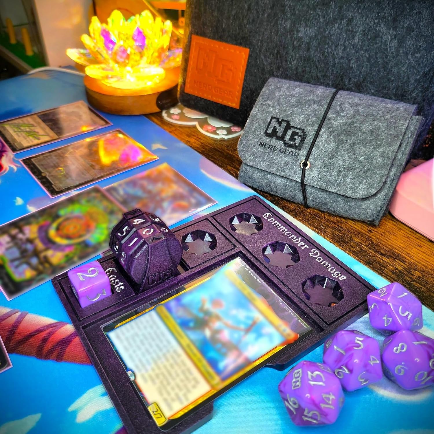 Tabletop gaming setup featuring MTG cards, purple dice, and a "Commander Damage" tracker